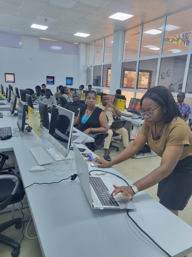 CloudTech Tribe volunteer assisting a trainee on a laptop during a session